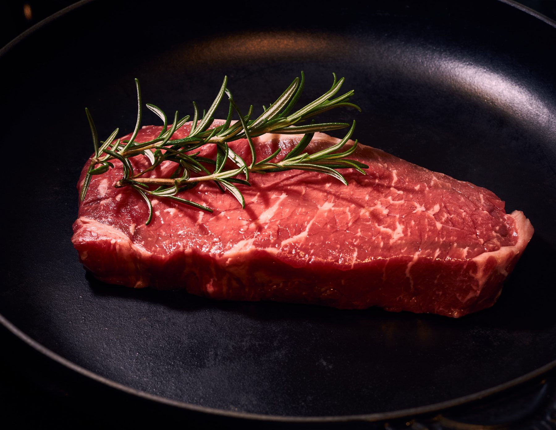 Marbled raw steak with fresh rosemary
